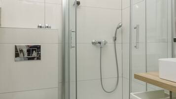 Ein modernes Badezimmer mit einer gläsernen Dusche, einer weißen Toilette und einem Holzkosmetikschrank.