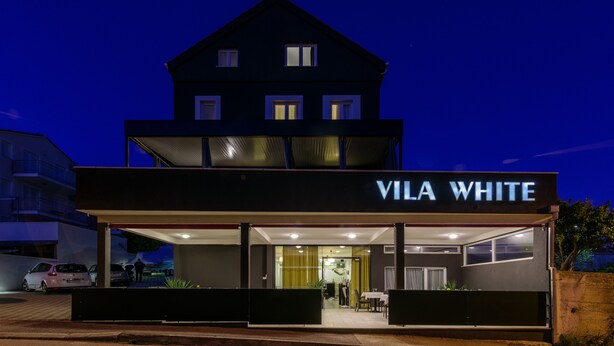 Een gebouw met twee verdiepingen, met een bord waarop 'VILA WHITE' staat.