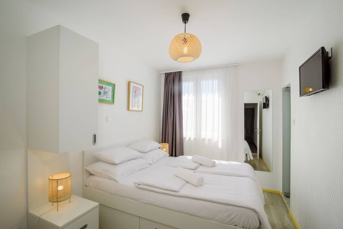 Una habitación de hotel moderna con una cama grande, lámparas de noche, televisión y obras de arte en las paredes.
