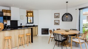Een moderne keuken met een centraal eiland, barstoelen, een eettafel met stoelen en een open haard.