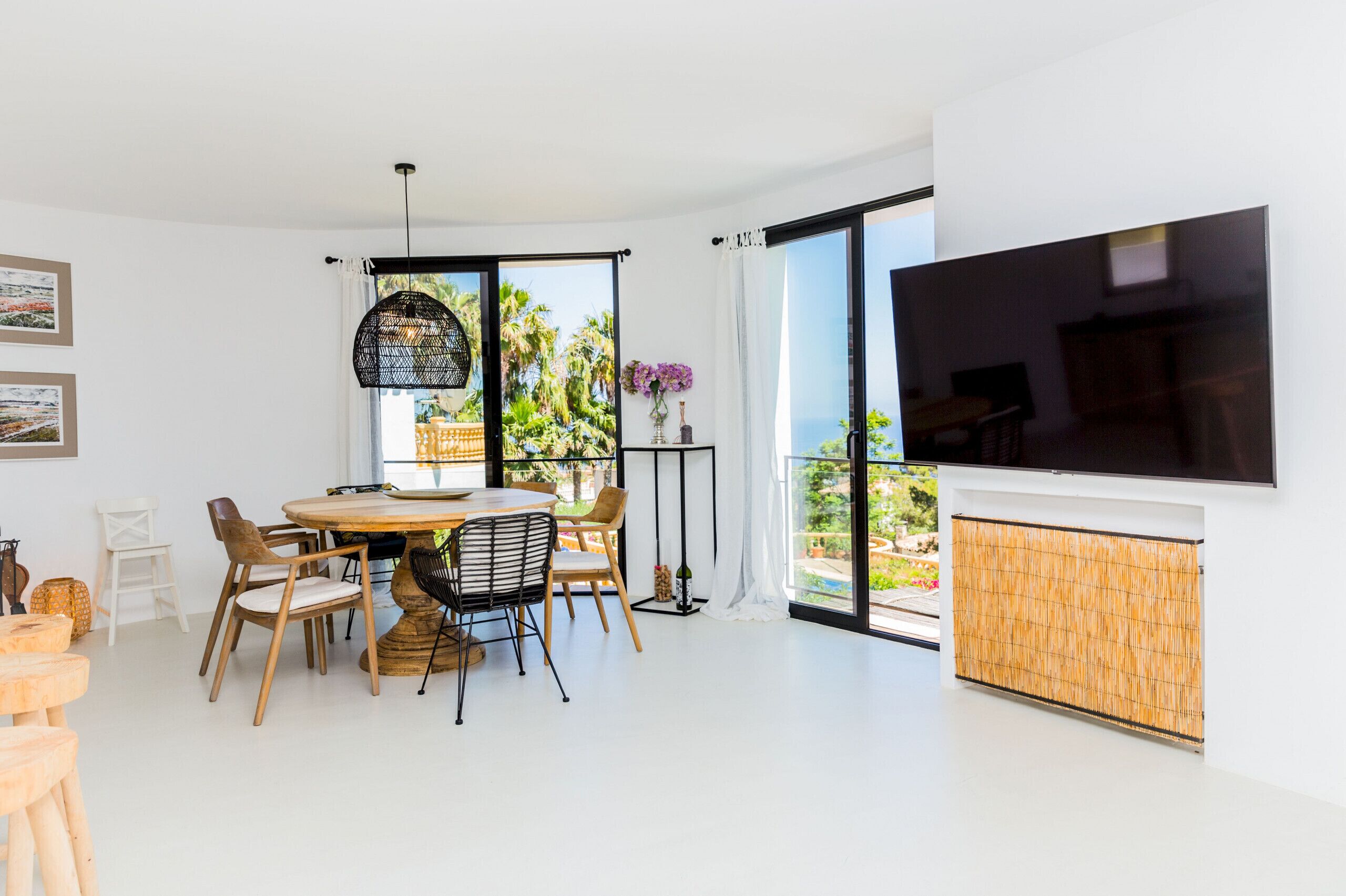 Una sala de estar moderna con comedor, ventanas amplias y un televisor de pantalla plana.