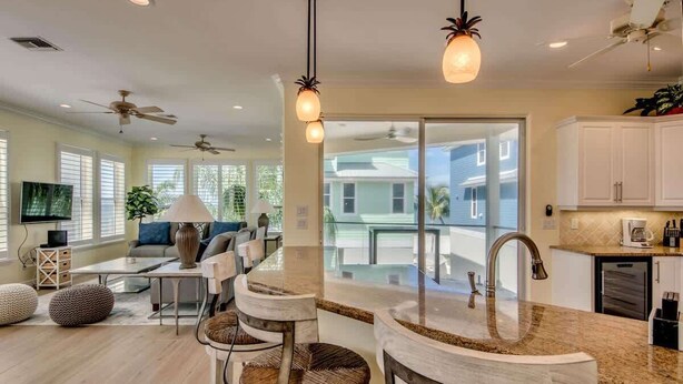 A modern kitchen with a central island, bar stools, and a large window overlooking a residential area.
