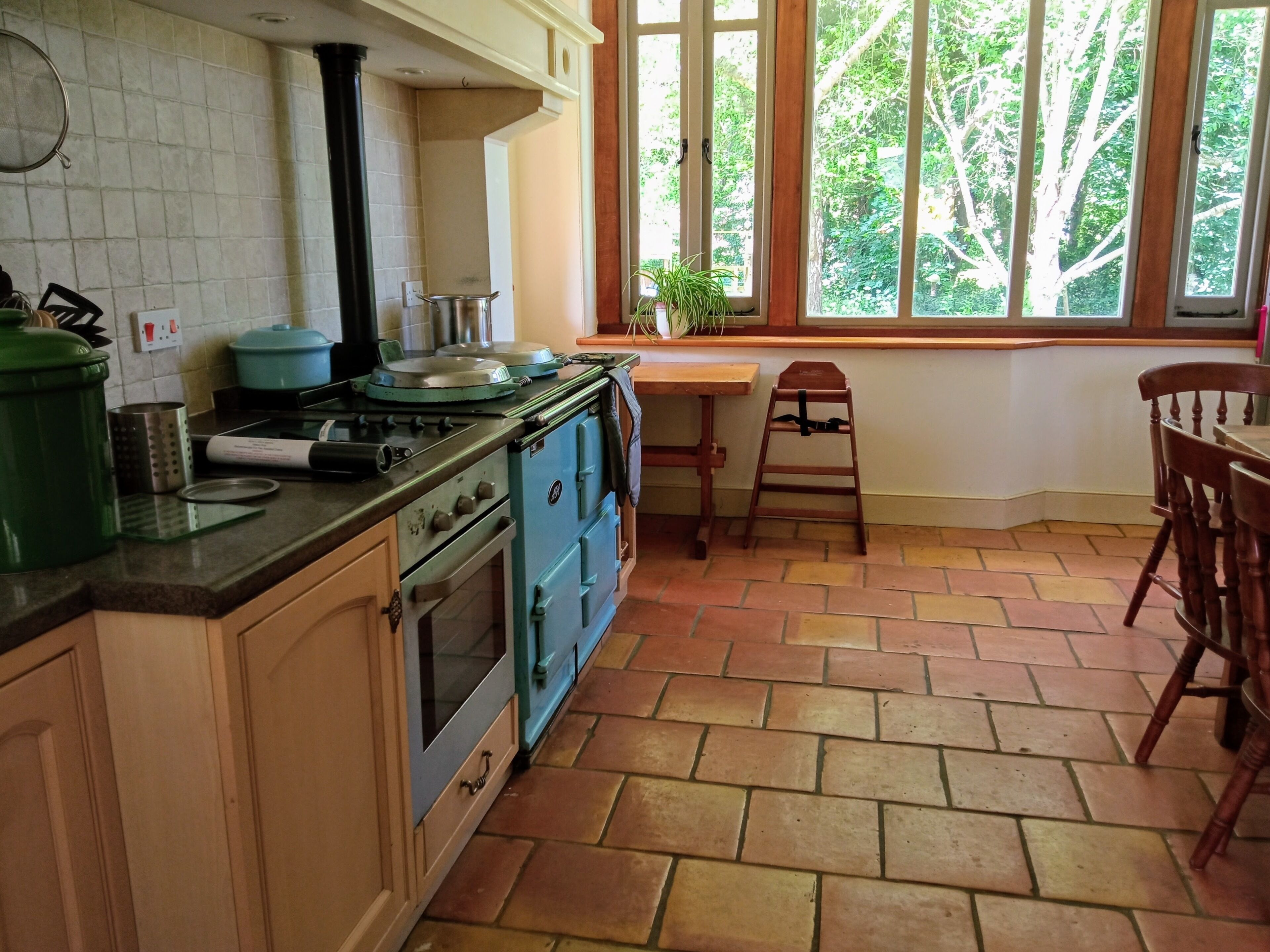 A kitchen with a stove, oven, and a window with a view of trees.