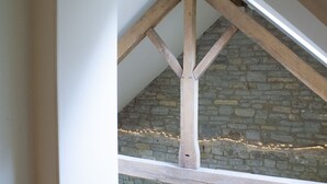 A stone wall with wooden beams and string lights.