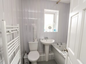 A small, white bathroom with a toilet, sink, and bathtub. - 11 Bro Celyn (Holyhead)