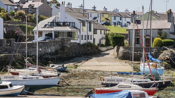 A harbor with boats docked, a narrow pathway between buildings, and a clear sky. - 11 Bro Celyn (Holyhead)