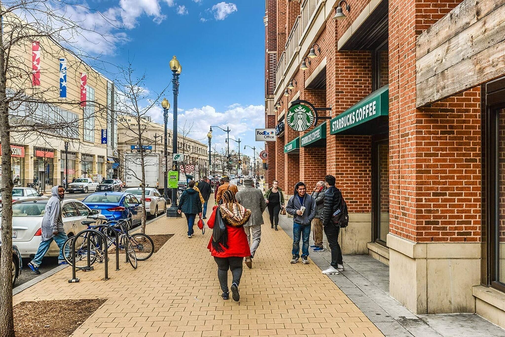 A street with pedestrians, a Starbucks Coffee, and a FedEx Office sign.