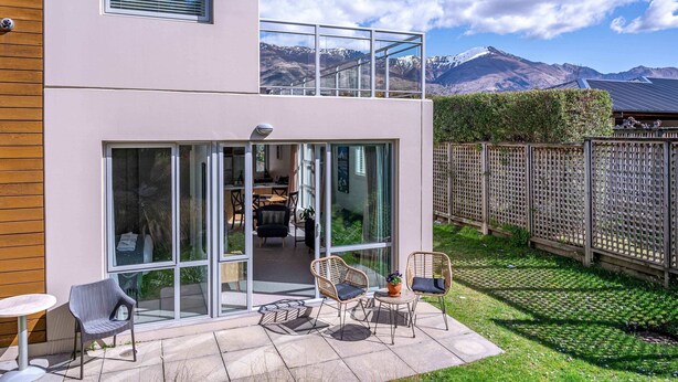 Een modern gebouw met twee verdiepingen en een glazen balkon met uitzicht op een bergachtig landschap.