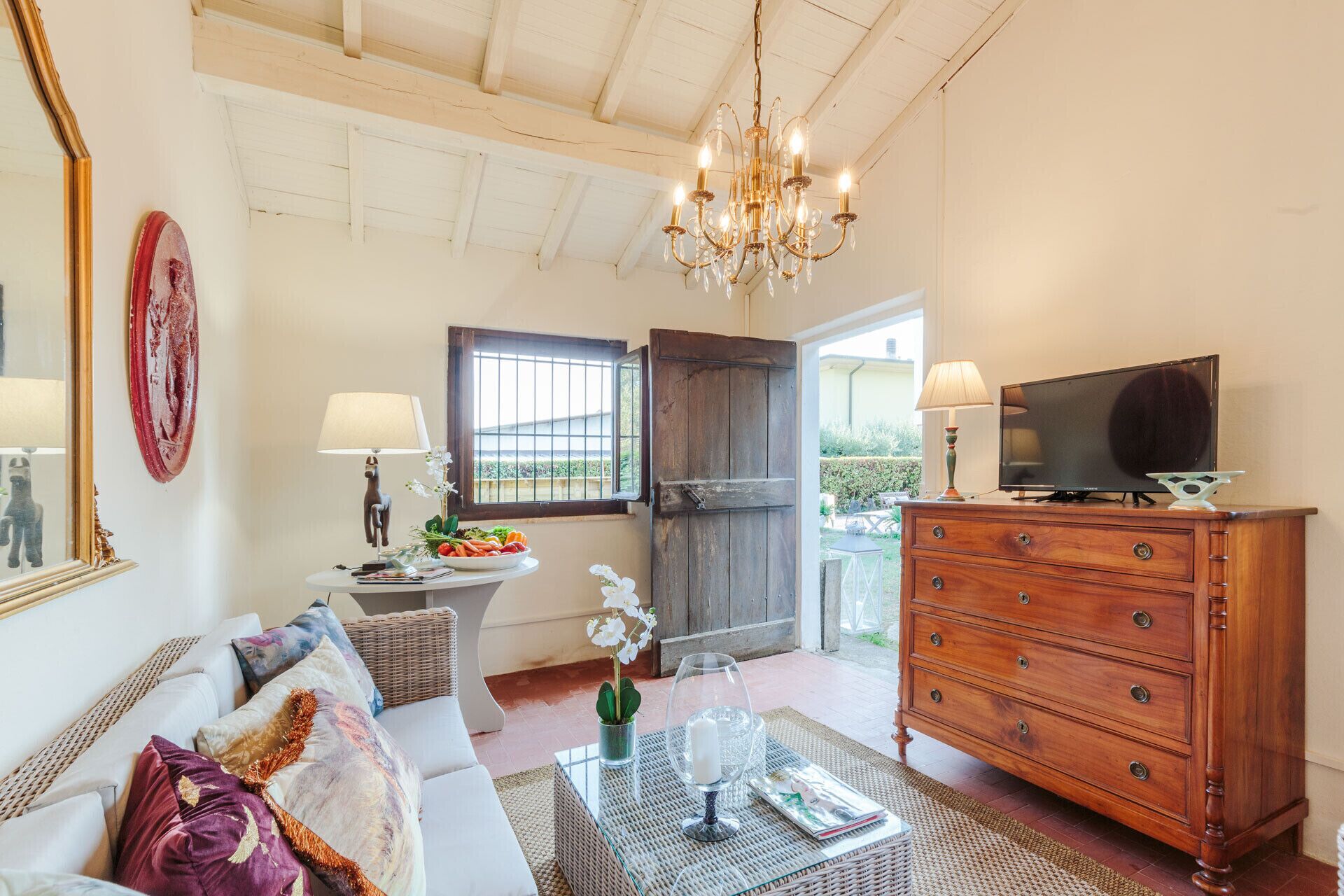 A living room with a sofa, coffee table, wooden dresser, and a television.