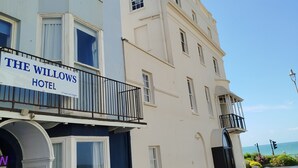 Un hotel llamado 'The Willows Hotel' con un letrero, un balcón y vista al mar.