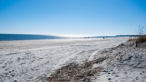 Ein weiter Sandstrand mit blauem Himmel und ruhiger See.