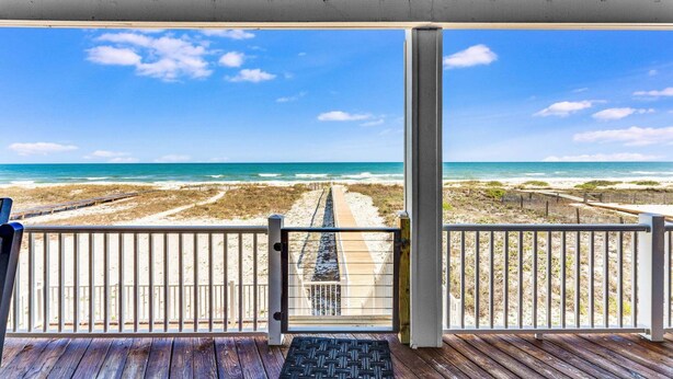 Eine Holzterrasse mit Blick auf Strand und Meer.
