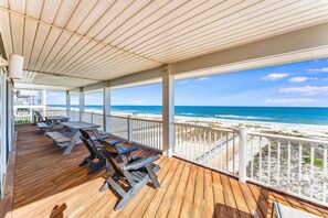 A covered deck with wooden benches and a view of the beach.