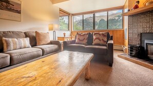 A cozy living room with a sofa, a wooden coffee table, and a fireplace. - Perfect Ski-in/out condo Center Village, Free Parking, WiFi, Amazing views (Copper Mountain)