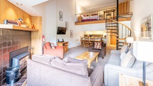 A spacious living area with a fireplace, a dining table, and a staircase leading to an upper level. - Perfect Ski-in/out condo Center Village, Free Parking, WiFi, Amazing views (Copper Mountain)