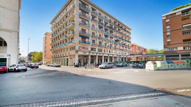 Um hotel com vários andares, varandas, área de estacionamento e vista para a rua.