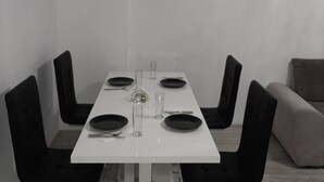 A dining table with four chairs, each with a black cushion. The table is set with plates, cutlery, and glasses. - 2 Bed-aircon-free Parking-city Centre (Chiajna)