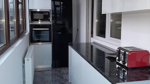 A compact kitchen with a built-in oven, a microwave, and a red toaster on a black countertop. - 2 Bed-aircon-free Parking-city Centre (Chiajna)