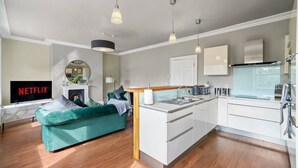 Un apartamento moderno con sala de estar, cocina y un televisor mostrando 'NETFLIX'.