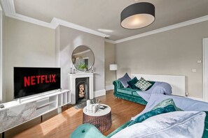 A modern living room with a flat-screen TV, a fireplace, a sofa, and a round coffee table. - Luxury Yorkshire Apartment 4 - Parking (Wakefield)