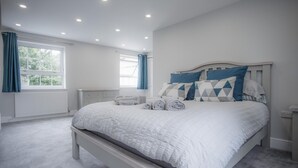 Una camera da letto con un letto grande, un comodino, una finestra con tende e un termosifone.