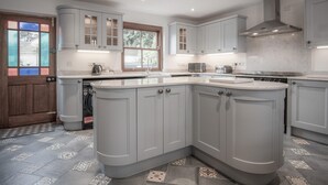 Una cucina moderna con mobili bianchi, piano cottura integrato e un'ampia finestra che offre luce naturale.