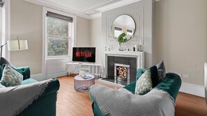 Ein Wohnzimmer mit Kamin, Fernseher und zwei grünen Sofas.