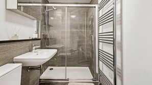 Ein modernes Badezimmer mit einer Glaskabinentrennung, einem weißen Waschbecken und einem Handtuchhalter.