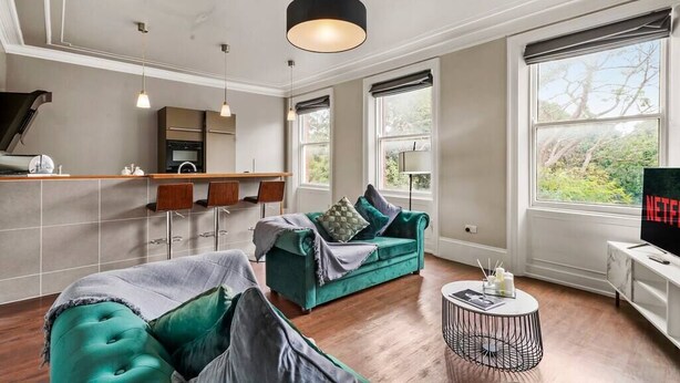 Ein modernes Wohnzimmer mit einem grünen Sofa, einem runden Couchtisch und einem Fernseher auf einem Schrank.