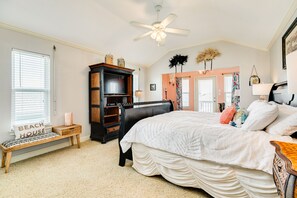 A bedroom with a large bed, a wooden bench, a TV stand, and a ceiling fan.