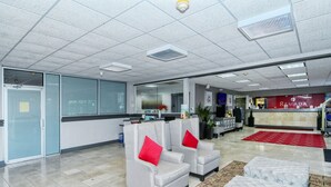 A modern lobby with a reception desk, seating area, and a patterned rug.