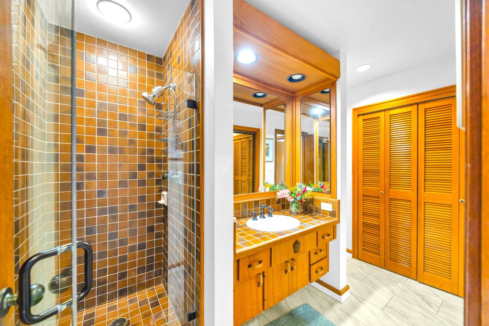 Een badkamer met een douche, wastafel en houten kasten.