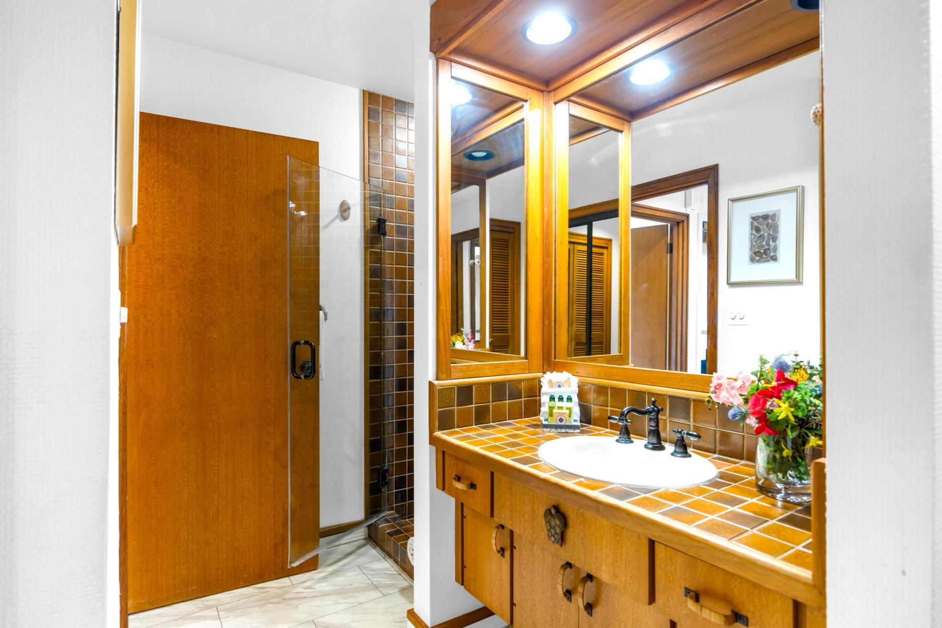 A bathroom with a wooden vanity, a large mirror, and a shower area.