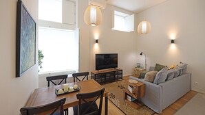 A modern living room with a dining area, a flat-screen TV, and a grey sofa. - FLH Gaia Homey Winery Flat (Vila Nova de Gaia)