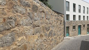 A stone wall adjacent to a building with multiple windows and doors. - FLH Gaia Homey Winery Flat (Vila Nova de Gaia)