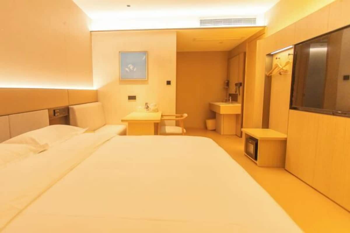 Una habitación de hotel con una cama grande, un escritorio pequeño, un lavamanos y un espejo.