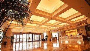 Eine geräumige Lobby mit hoher Decke, großen Fenstern und einer Rezeption.