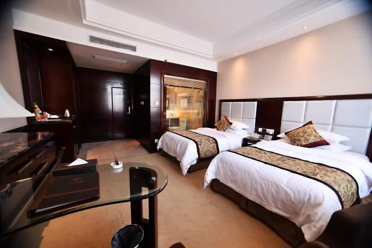 Una habitación de hotel con dos camas, un escritorio y un minibar.