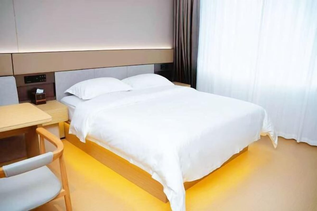 A hotel room with a bed, a desk, and a chair.