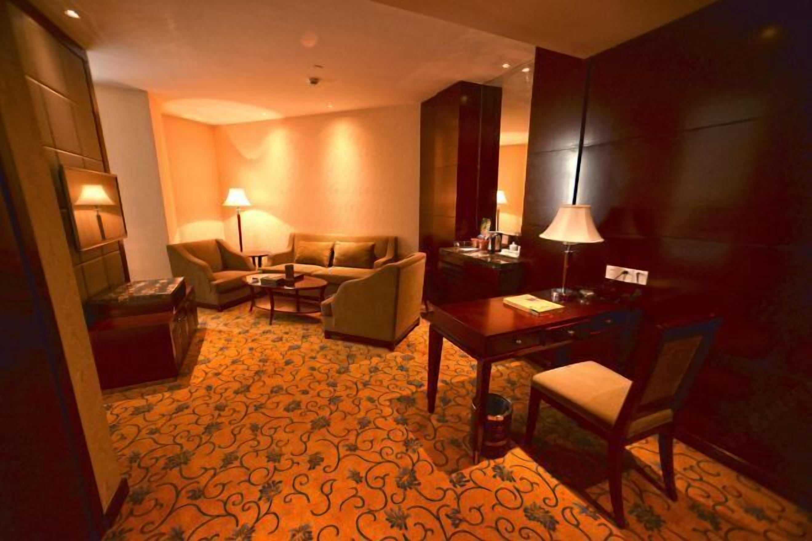 Une chambre d’hôtel équipée d’un canapé, de fauteuils, d’une table à manger et d’une lampe.