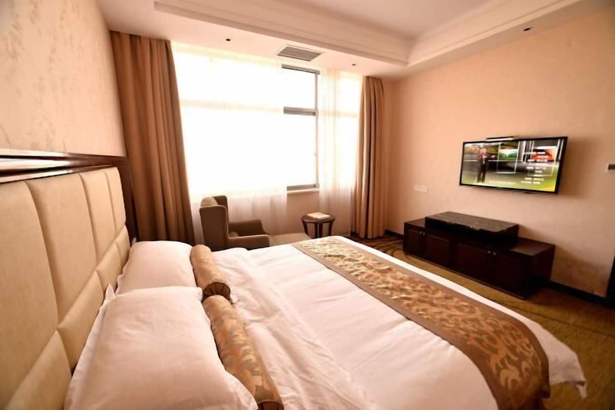 Una habitación de hotel con una cama grande, un televisor en la pared y una mesita.