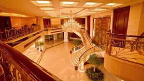 Eine prachtvolle Hotelhalle mit einer zentralen Treppe, mehreren Stockwerken und einem Kronleuchter.