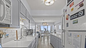 A modern kitchen with white cabinets, a large island, and a view to the outside.