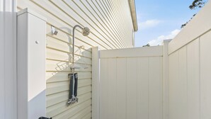 A white exterior wall with a metal gate and a metal hose attached to it.