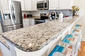 A kitchen with a granite countertop, stainless steel appliances, and white cabinetry.