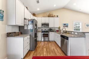 Una cocina moderna con armarios blancos, electrodomésticos de acero inoxidable y piso de madera.
