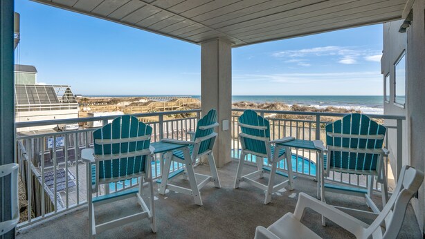 A covered outdoor area with a pool, chairs, and a view of the ocean.