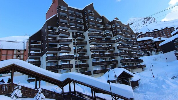 Ett hotell med flera våningar och balkonger, omgivet av snötäckta byggnader och berg.