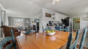 A dining area with a wooden table, teal chairs, and a bowl of green apples. - Bayside Cottage steps from Rock Hall Harbor (Rock Hall)
