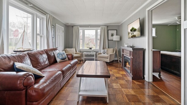 A spacious living room with a leather sofa, a wooden coffee table, and a fireplace. - Bayside Cottage steps from Rock Hall Harbor (Rock Hall)